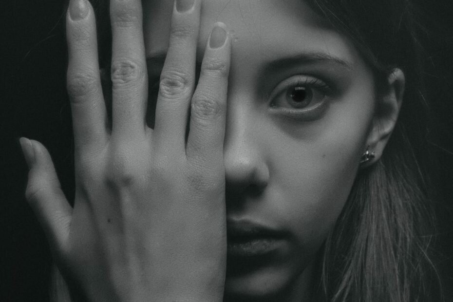 grayscale photo of woman covering her face by her hand