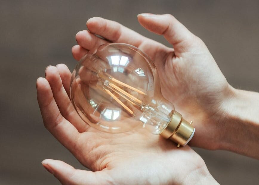 unrecognizable woman demonstrating light bulb in hands